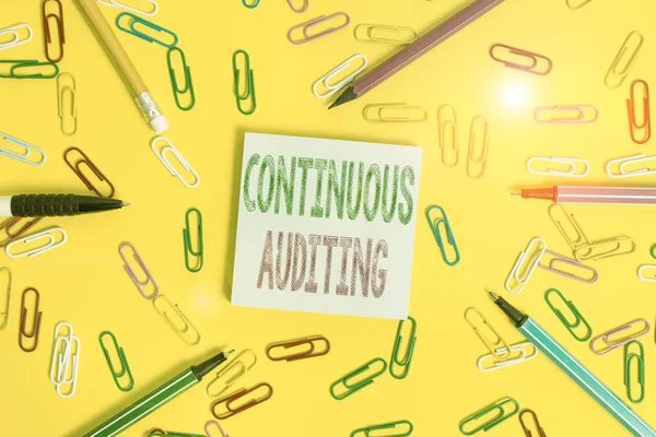 Handwriting text writing Continuous Auditing. Conceptual photo Internal process that examines accounting practices Flat lay above empty paper with copy space pencils and colored paper clips