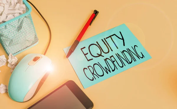 Conceptual hand writing showing Equity Crowdfunding. Concept meaning raising capital used by startups and earlystage company crumpled paper in bin placed next to modern gadget and stationary