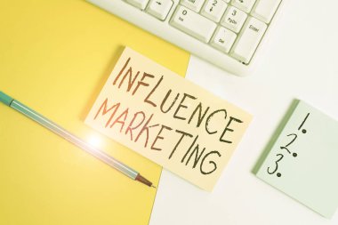 Writing note showing Influence Marketing. Business concept for Using key leaders to drive a brand s is message to market Paper with copy space and keyboard above orange background table