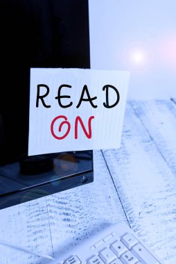 Okuma Açık 'ı gösteren metin işareti. İş fotoğrafı metni, beyaz klavyenin yanındaki siyah bilgisayar monitörü ekranına bantlanmış bir not kağıdı hakkında bilgi edinmek için okumaya zaman harcıyor