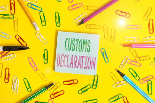 Handwriting text writing Customs Declaration. Conceptual photo Official document showing goods being imported Flat lay above empty paper with copy space pencils and colored paper clips