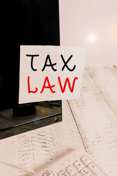 Text sign showing Tax Law. Business photo text governmental assessment upon property value or transactions Notation paper taped to black computer monitor screen near white keyboard