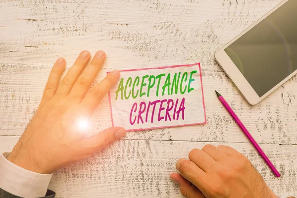 Conceptual hand writing showing Acceptance Criteria. Concept meaning Specified indicators in assessing the ability of a part Hand hold note paper near writing equipment and smartphone
