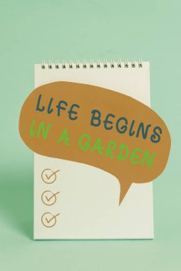 Word writing text Life Begins In A Garden. Business photo showcasing Agriculture Plants growing loving for gardening Standing blank spiral notepad speech bubble lying cool pastel background