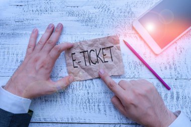 Text sign showing E Ticket. Business photo showcasing Digital ticket that is as valid as a paper ticket or its equivalent Hand hold note paper near writing equipment and modern smartphone device