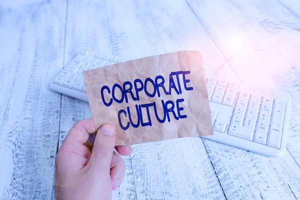 Writing note showing Corporate Culture. Business concept for beliefs and attitudes that characterize a company Man holding colorful reminder square shaped paper wood floor