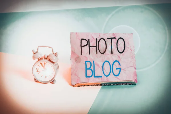 Handwriting text writing Photo Blog. Conceptual photo form of photo sharing and publishing in the format of a blog Mini size alarm clock beside a Paper sheet placed tilted on pastel backdrop