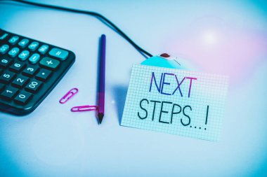 Handwriting text Next Steps. Conceptual photo something you do after you have finished doing first one Wire mouse clips marker calculator squared paper sheet colored background
