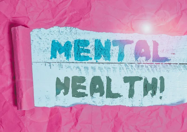 Conceptual hand writing showing Mental Health. Concept meaning demonstratings condition regard to their psychological well being Cardboard which is torn placed above a wooden classic table