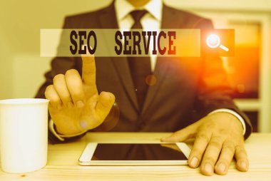 Seo Servisini gösteren kavramsal el yazısı. Konsept, web sitesinin görünürlüğünü arttırmak için teknik ve prosedür anlamına gelir. Erkek insan resmi giysiler giyer. Hitech akıllı telefonu kullanın.