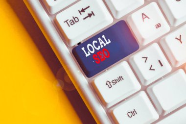 Yerel Seo'u gösteren bir not yazıyorum. İşletmelerin yerel müşterilere ürün ve hizmetleri tanıtmasına yardımcı olmak için iş konsepti Beyaz bilgisayar klavyesi beyaz arka planın üzerinde not kağıdı ile