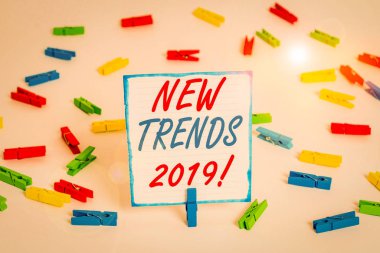 Yeni Eğilimler 2019 el yazısı metni. Renkli çamaşır iğnesi kağıtlarının gelişmekte olduğu kavramsal fotoğraf genel yönü boş hatırlatıcı beyaz zemin arkaplan ofisi