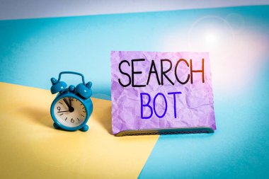 El yazısı metni yazan Arama Robotu. Kavramsal fotoğraf. İnternet ya da ağ üzerinden otomatik görevleri çalıştıran bir program. Pastel arka plana yaslanmış kağıdın yanında Mini boyutunda alarm saati.
