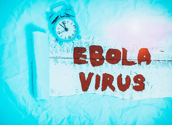 Conceptual hand writing showing Ebola Virus. Concept meaning a viral hemorrhagic fever of huanalysiss and other primates Alarm clock and torn cardboard on a wooden classic table backdrop