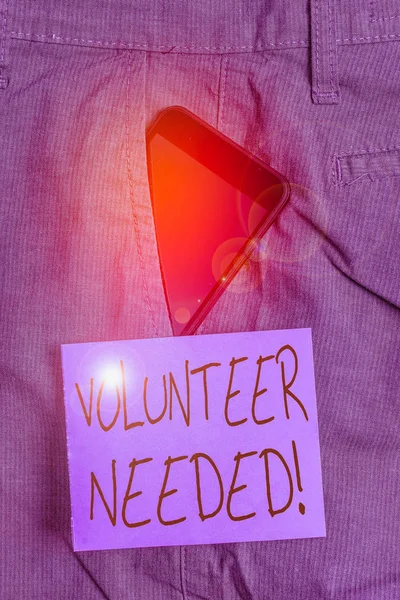 Word writing text Volunteer Needed. Business photo showcasing asking demonstrating to work for organization without being paid Smartphone device inside formal work trousers front pocket near note paper