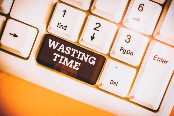 Text sign showing Wasting Time. Business photo showcasing act of spending time doing something that is unnecessary White pc keyboard with empty note paper above white background key copy space