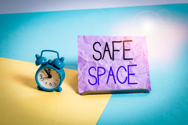 Handwriting text writing Safe Space. Conceptual photo a place or room in which you are protected from harm or danger Mini size alarm clock beside a Paper sheet placed tilted on pastel backdrop