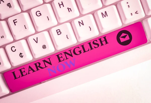 Text sign showing Learn English Now. Business photo showcasing gain or acquire knowledge and skill of english language White pc keyboard with empty note paper above white background key copy space