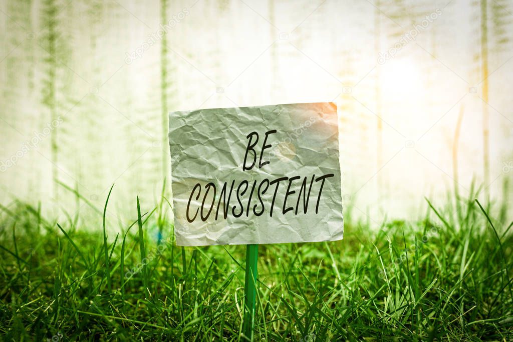 Conceptual hand writing showing Be Consistent. Concept meaning Uniform Persistent Firm Unalterable Even Unchanging Rapport Plain paper attached to stick and placed in the grassy land