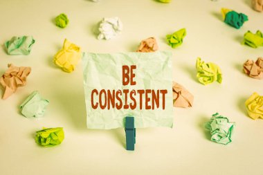 El yazısı, tutarlı ol. Kavramsal fotoğraf Üniforması Değişmez Firma Değişmez Rapport Renkli kağıtlar boş hatırlatıcı beyaz zemin çamaşır mandalı