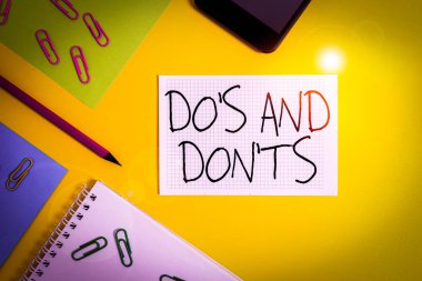 Do S ve Don 'u gösteren bir not yazıyorum. Bazı faaliyet veya eylemlere ilişkin kurallar veya gelenekler için iş konsepti Kağıt kağıtlar kare kalem raptiyeleri akıllı telefon renkli arkaplan