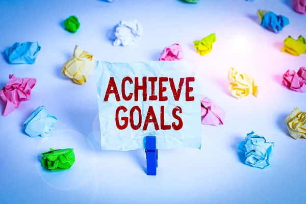 Handwriting text Achieve Goals. Conceptual photo Results oriented Reach Target Effective Planning Succeed Colored crumpled papers empty reminder white floor background clothespin