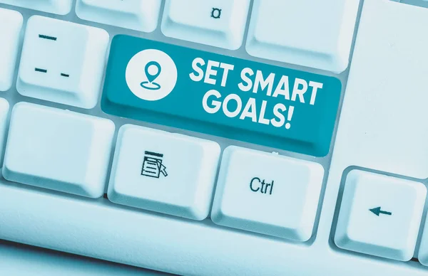 Writing note showing Set Smart Goals. Business concept for list to clarify your ideas focus efforts use time wisely White pc keyboard with note paper above the white background