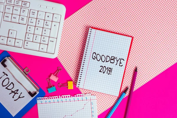 Writing note showing Good Bye 2019. Business concept for express good wishes when parting or at the end of last year Writing equipments and computer stuffs placed above colored plain table