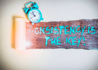 Handwriting text writing Consistency Is The Key. Conceptual photo by Breaking Bad Habits and Forming Good Ones Alarm clock and torn cardboard placed above a wooden classic table backdrop clipart