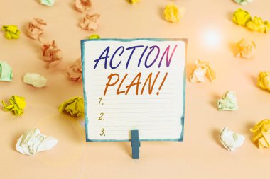 El yazısı Eylem Planı. Belirli bir süre için kavramsal fotoğraf önerisi stratejisi veya eylem planı Renkli buruşmuş kağıtlar boş hatırlatıcı pembe zemin çamaşır mandalı