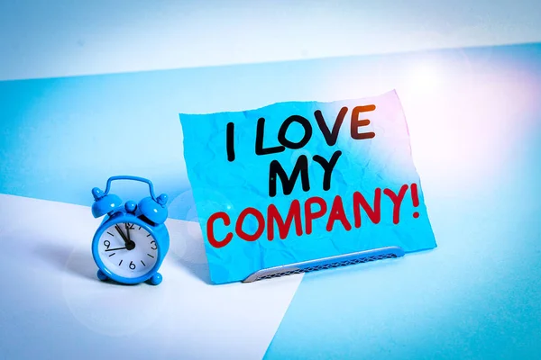 Writing note showing I Love My Company. Business concept for tell why admire their job and workplace Alarm clock beside a Paper sheet placed on pastel backdrop