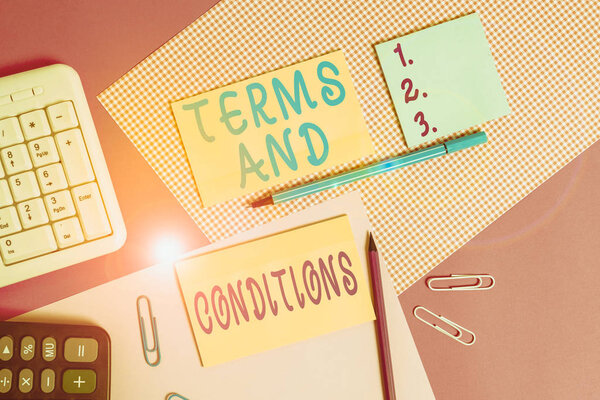 Text sign showing Terms And Conditions. Business photo showcasing rules that apply to fulfilling a particular contract Writing equipments and computer stuffs placed above colored plain table