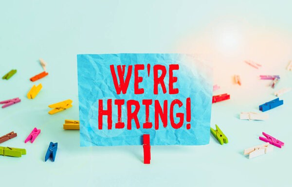 Writing note showing We Re Hiring. Business concept for recently employ someone or pay someone to do particular job Colored clothespin rectangle square shaped paper light blue background