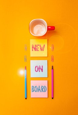 Text sign showing New On Board. Business photo text Welcome to the team Adaptation Collaboration Someone hired Coffee cup blank colored sticky note two ballpoints clips yolk background clipart