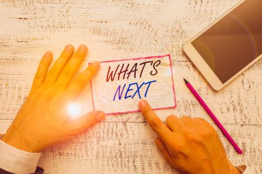 Writing note showing What S Is Next. Business concept for talking about the future or what is coming after the present Hand hold note paper near writing equipment and smartphone