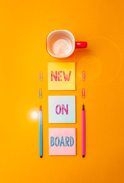 Text sign showing New On Board. Business photo text Welcome to the team Adaptation Collaboration Someone hired Coffee cup blank colored sticky note two ballpoints clips yolk background