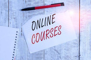 Çevrimiçi kursları gösteren not yazılıyor. Kurslar için iş konsepti, bir web tarayıcısına bir dizi ders sunar Yırtık kağıt ve defter kağıdıyla ahşap masanın üstüne yerleştirilmiş bir kalem.