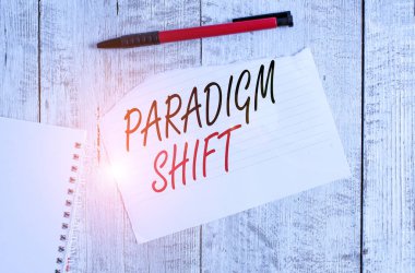 Paradigma Değişimini gösteren not yazılıyor. Temel yaklaşım değişikliği için iş kavramı ya da temelde varsayımlar Yırtık kağıt ve defter kağıtları Tahta masa üzerine yerleştirilmiş bir kalem ile