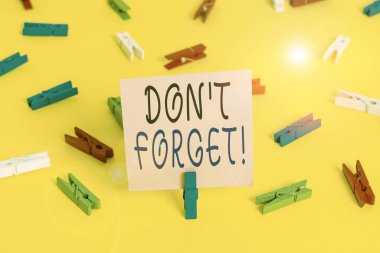 Mesaj işareti Don 't Forget' u gösteriyor. İş fotoğrafı sergisi birisine önemli bir gerçeği veya detayı hatırlatmak için kullanılır Renkli çamaşır iğnesi kağıtları boş hatırlatıcı sarı zemin arka plan ofisi