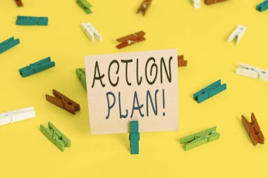 Eylem Planı 'nı gösteren metin işareti. İş fotoğrafı gösterimi önerilen strateji veya belirli bir süre için eylem planı Renkli çamaşır iğnesi kağıtları boş hatırlatıcı sarı zemin arka plan ofisi