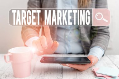 El yazısı, hedef pazarlama. Ürünü satın alacak potansiyel müşterilerden oluşan kavramsal bir fotoğraf grubu. İş kadını masada cep telefonu ve kahve ile oturuyor.