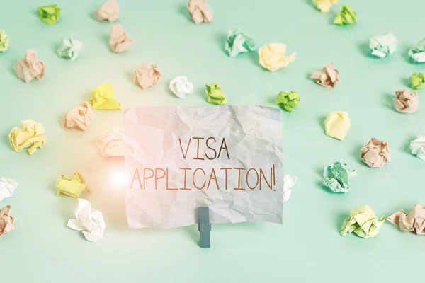 Writing note showing Visa Application. Business concept for Form to ask permission travel or live in another country Colored crumpled papers empty reminder blue floor background clothespin