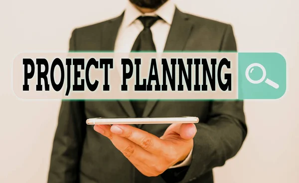 Conceptual hand writing showing Project Planning. Concept meaning plan and subsequently report progress within the project Male human wear formal work suit hold smartphone using hand