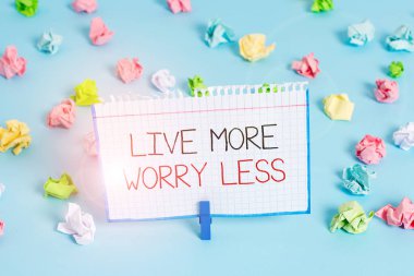 El yazısı. Daha az endişelen. Kavramsal fotoğraf iyi bir tutum motivasyonuna sahip ol dikkatsiz ol hayatın tadını çıkar renkli buruşuk kağıtlar boş mavi zemin çamaşır mandalı