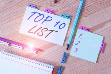 Top 10 Listesini gösteren kavramsal el yazısı. Kavram, belirli bir listedeki en önemli ve en başarılı on öğe anlamına gelir Renkli buruşmuş kağıtlar ahşap zemin çamaşır mandalı