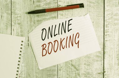 Online Rezervasyon 'u gösteren not yazıyorum. İş seyahatlerini analiz etmek için kullanılan iş konsepti. Yırtık kağıt ve defter kağıdı ile ahşap masanın üzerine yerleştirilmiş bir kalem.