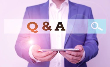 Kelime yazma metni Q ve A. Soru sorulup cevaplanması olarak tanımlanan iş konsepti mavi süitli ve beyaz gömlekli adamın elinde cep telefonu bulunuyor.