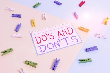 Do S ve Don 't T.S.' i gösteren bir not yazıyorum. Bazı faaliyet veya eylemlere ilişkin kurallar veya gelenekler için iş konsepti Sarı mavi arka planlı renkli çamaşır mandalı kağıt anımsatıcı