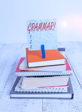 Gramer gösteren kavramsal el yazısı. Kavram anlamı tüm sistem yapısı söz dizimi ve morfoloji yığını dizilmiş kitaplar dizüstü not defteri renk hatırlatıcısı beyaz ahşap