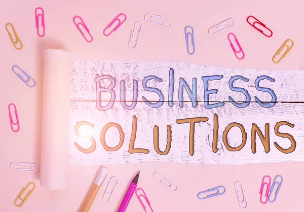 Text sign showing Business Solutions. Business photo showcasing ideas used to help a company achieve its objectives Stationary and torn cardboard placed above a wooden classic table backdrop